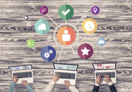 Group of three people with devices in hands working together as symbol of networking and communicationの写真素材