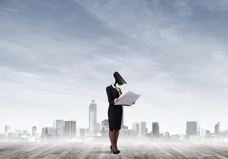 Faceless businesswoman with camera zoom instead of head against cityscape backgroundの写真素材