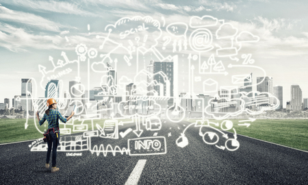 Back view of engineer woman in hardhat outdoor and sketched concept on screenの写真素材