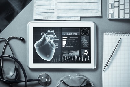 White tablet pc and doctor tools on gray surfaceの写真素材