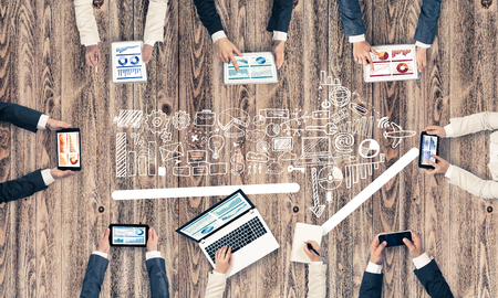 Group of people with devices in hands working together as symbol of networking and communicationの写真素材