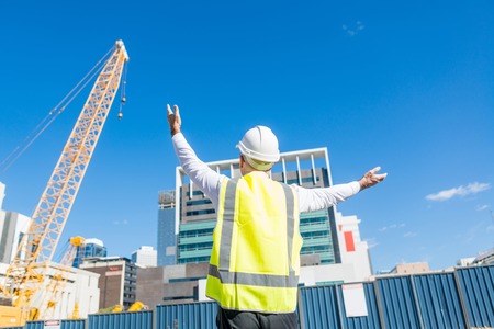 Engineer man in helmet and jacket controlling outdoor construction siteの写真素材