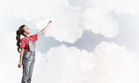 Cute kid girl in overalss with paper plane in handの写真素材