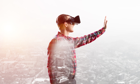 Young man with virtual reality headset or 3d glasses over cityscape backgroundの写真素材