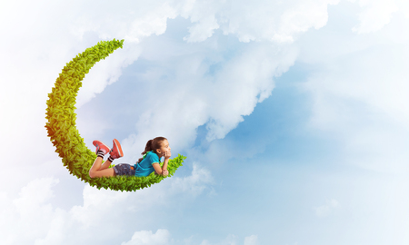 Cute kid girl on green moon floating in day skyの写真素材