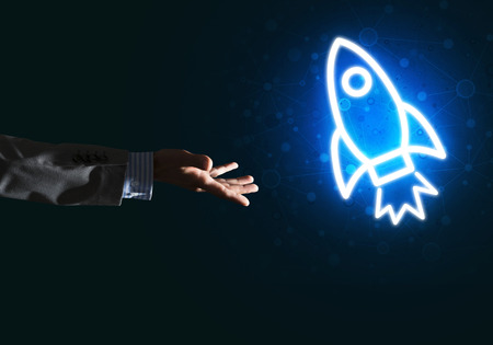 Rocket glowing icon and businessman hand on dark backgroundの写真素材