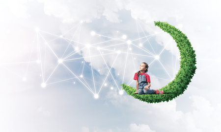 Cute kid girl sitting on green moon and social connection conceptの写真素材