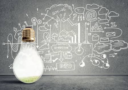 Glass glowing light bulb and business sketched ideas on wallの写真素材