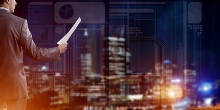 Rear view of businessman against virtual panel interface holding papers in handの写真素材