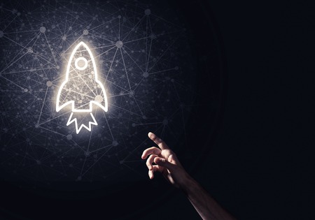 Rocket glowing icon and man hand on dark backgroundの写真素材