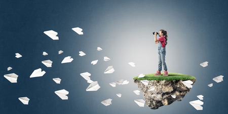 Cute kid girl sitting on floating island against concrete backgroundの写真素材