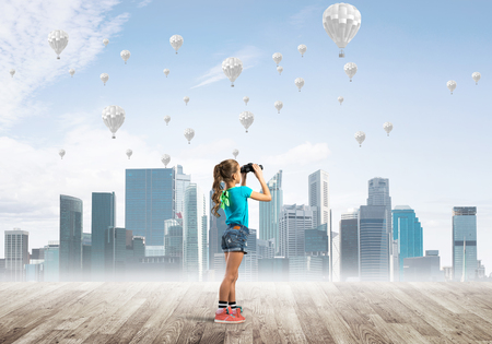Cute kid girl standing on wooden floor and aerostats flying in airの写真素材
