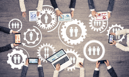 Group of people with devices in hands working together as symbol of networking and communicationの写真素材
