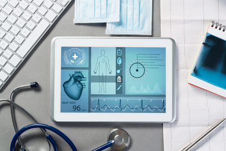 White tablet pc and doctor tools on gray surfaceの写真素材