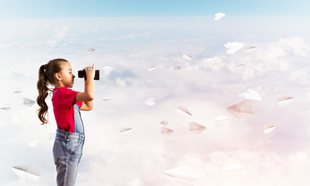 Little cute girl in overalls against sky background dreaming about futureの写真素材