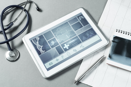 White tablet pc and doctor tools on gray surfaceの写真素材