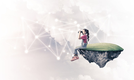 Cute girl on floating island looking in spyglass presenting social connection conceptの写真素材