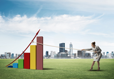 Young woman outdoors and growing graph presenting growth progressの写真素材