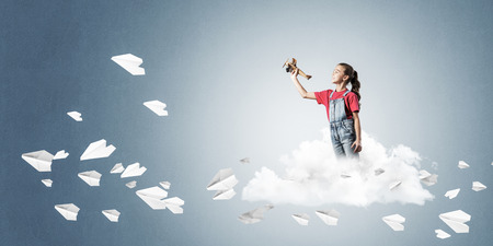 Cute kid girl on cloud and paper planes flying aroundの写真素材