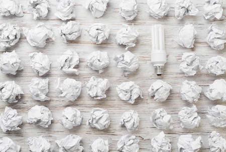 Many balls of crumpled paper and glowing light bulbの写真素材