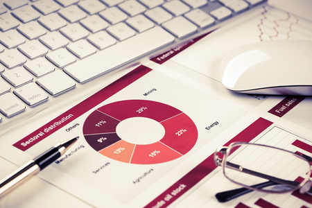 Business workplace with keyboard glasses and financial documents on tableの写真素材