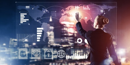 Back view of businesswoman working with virtual panel and night city at background