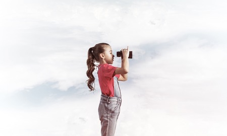 Little cute girl in overalls against sky background dreaming about futureの写真素材