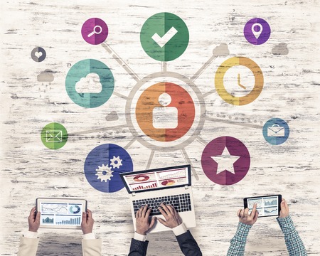 Group of three people with devices in hands working together as symbol of networking and communicationの写真素材