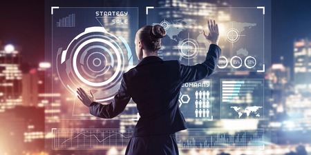 Back view of businesswoman working with virtual panel and night city at backgroundの写真素材