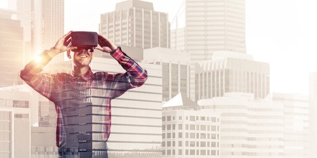 Young man with virtual reality headset or 3d glasses over cityscape backgroundの写真素材
