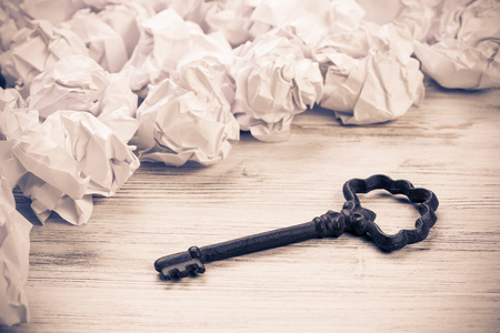 Vintage key among many balls of crumpled paperの写真素材