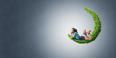 Cute kid girl on green moon and looking awayの写真素材
