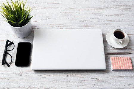 Still life photo of laptop notepad coffee glasses and other stuff on wooden tableの写真素材