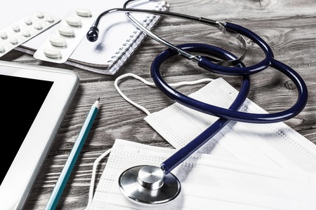 Doctors wooden table with white tablet and stethoscopeの写真素材