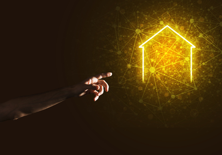 Hand of man touching with finger glowing home icon or symbolの写真素材