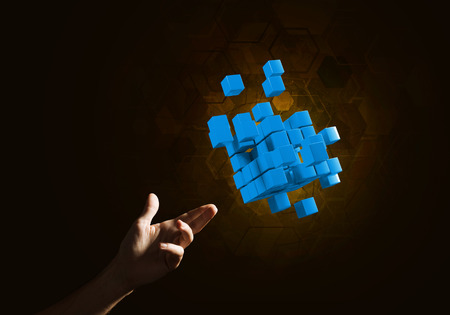 Close of man hand holding cube figure as symbol of innovation. Mixed media.の写真素材