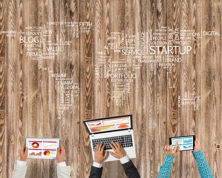 Group of people with devices in hands working together as symbol of networking and communicationの写真素材