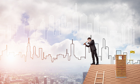 Young businessman in suit on roof edge. Mixed mediaの写真素材
