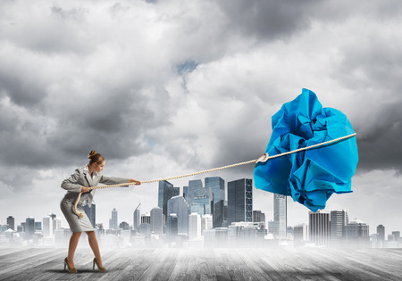 Young woman outdoors making huge paper ball moveの写真素材