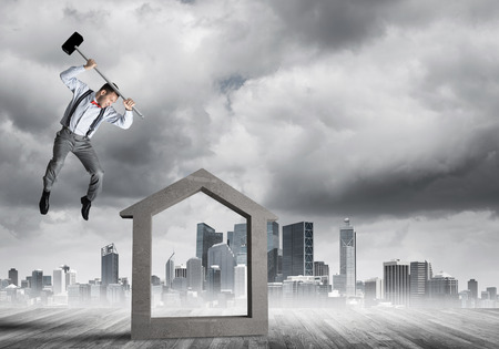Determined businessman going to break with hammer house concrete figureの写真素材