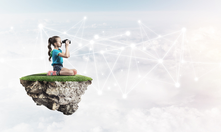 Cute girl on floating island looking in spyglass presenting social connection conceptの写真素材