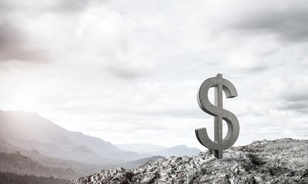 Stone dollar symbol outdoors on green hill as currency signの写真素材