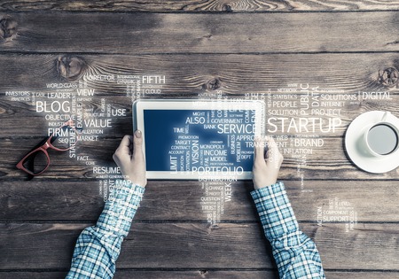 Top view of woman in checked shirt sitting at table with tablet pcの写真素材