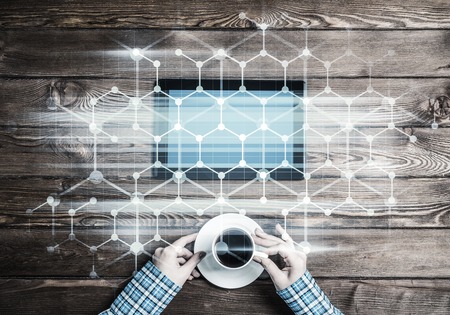 Top view of woman in checked shirt sitting at table and tablet deviceの写真素材
