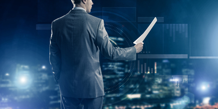 Rear view of businessman against virtual panel interface holding papers in handの写真素材