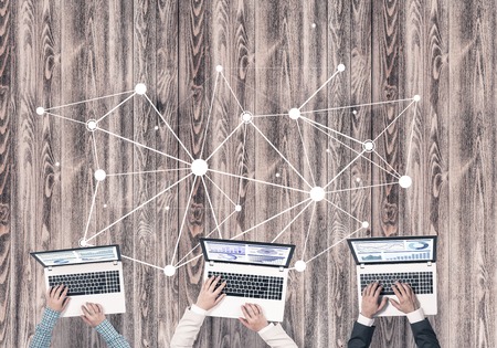 Group of three people with devices in hands working together as symbol of networking and communicationの写真素材