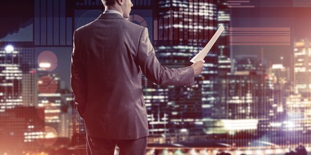 Rear view of businessman against virtual panel interface holding papers in handの写真素材