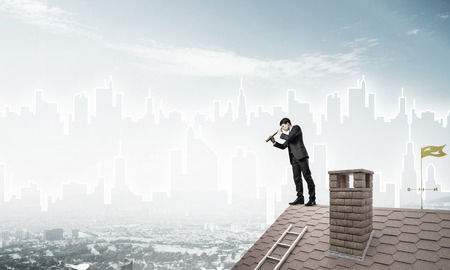 Young businessman in suit on roof edge. Mixed mediaの写真素材