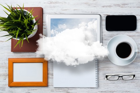 Top view of modern workplace with office stuff and cloud above presenting still office life. Mixed media.の写真素材