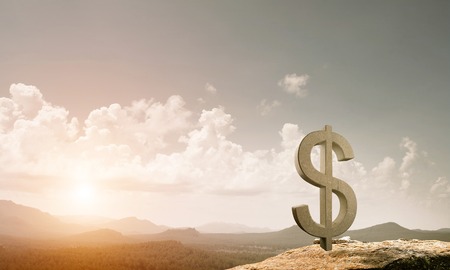 Stone dollar symbol outdoors on green hill as currency signの写真素材